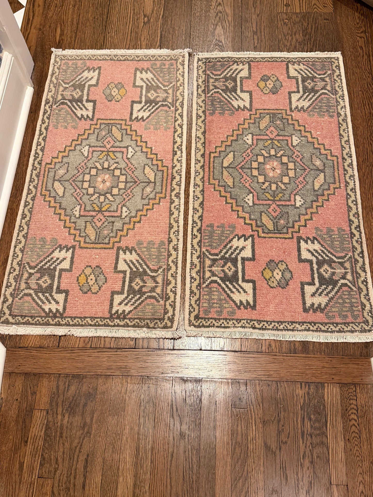 2 of 2 matching vintage Oushak mats in pink, cream, gray, and yellow, sized 1’8”x3’5”