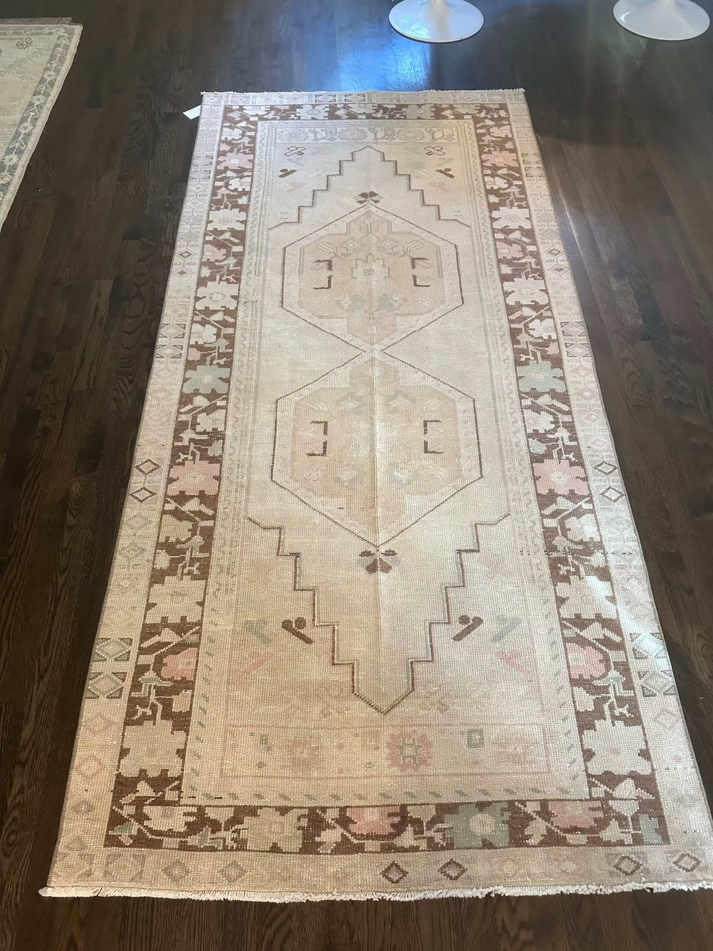 3’10” x 8'2" area rug with brown border on wooden floor