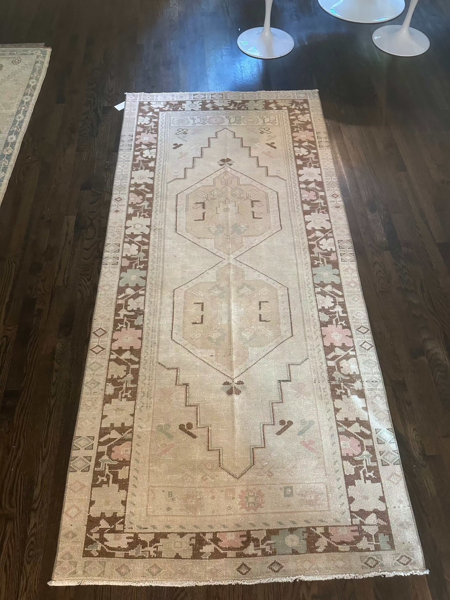 Vintage-style runner rug, measuring 3’10” x 8’2”, with geometric patterns and a decorative border on a hardwood floor.