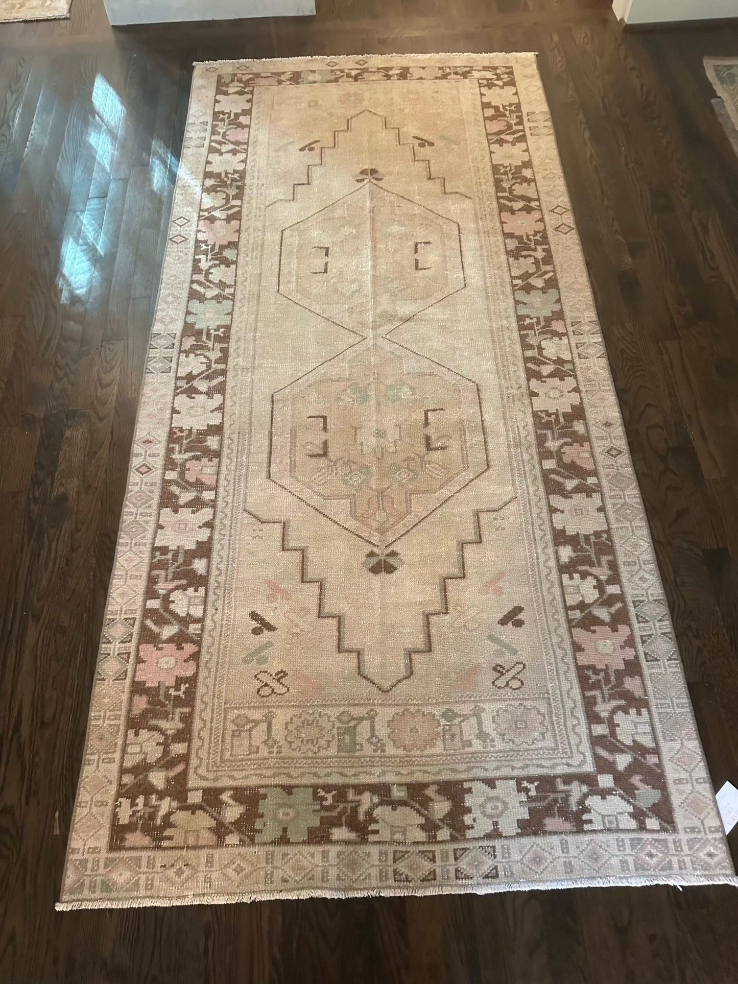 3’10” x 8'2" area rug with brown border on hardwood floor