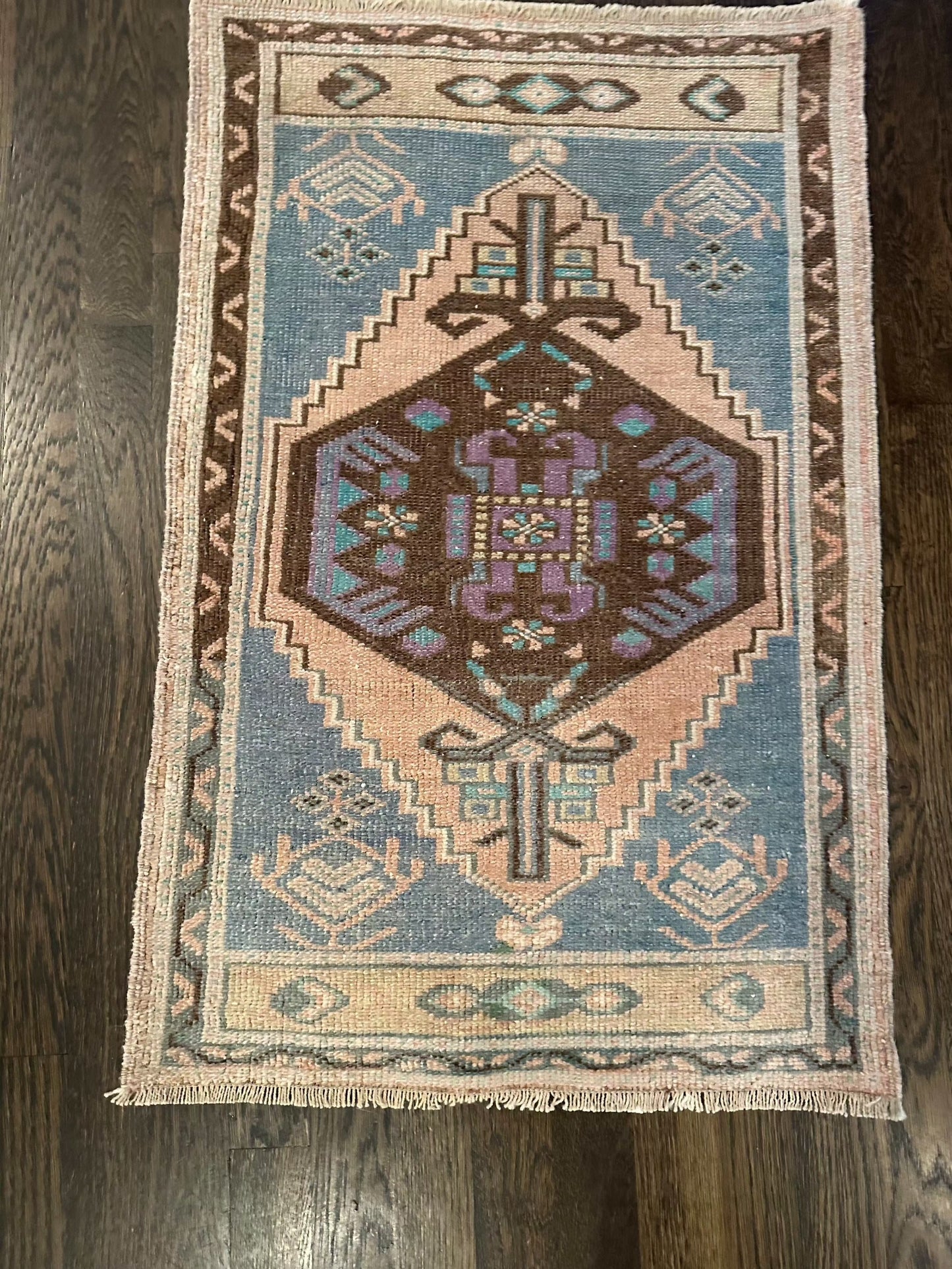 1’10” x 2’10” mini rug with vibrant colors of blue, turquoise, brown, blush, and purple.