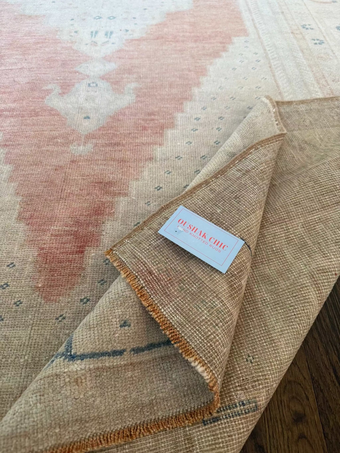 4’10” x 9’6” area rug with beige base and muted red, blue, sage, grey, and ivory accents