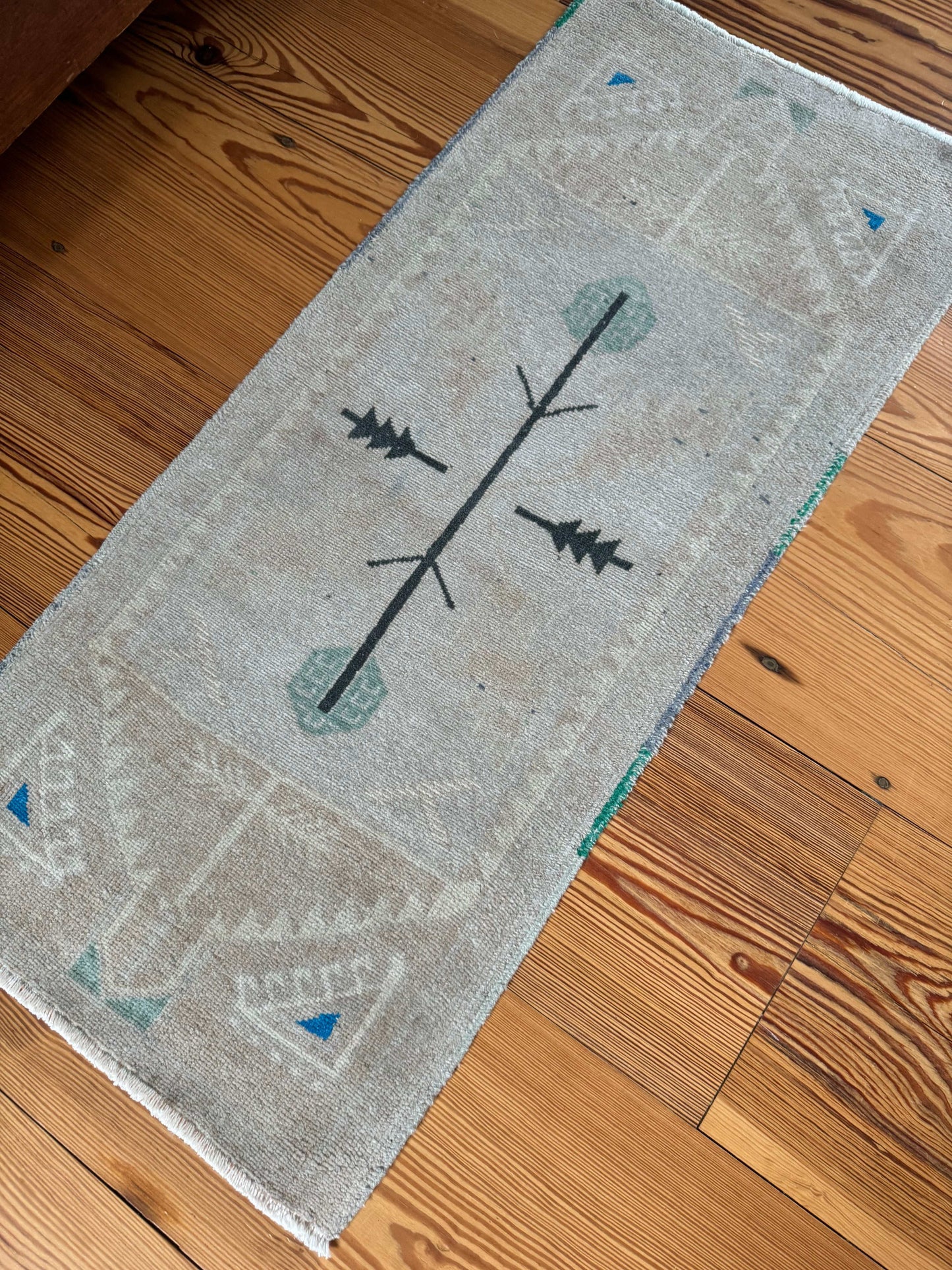 Small rug with natural tones and blue, green, gray accents measuring 1'8" x 3'9"