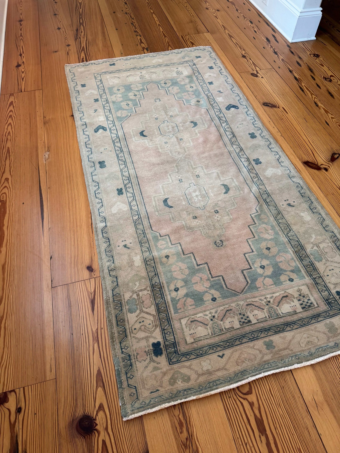 3’11”x8’0” vintage Oushak area rug in light beige, cream, pink, and blue on wooden floor