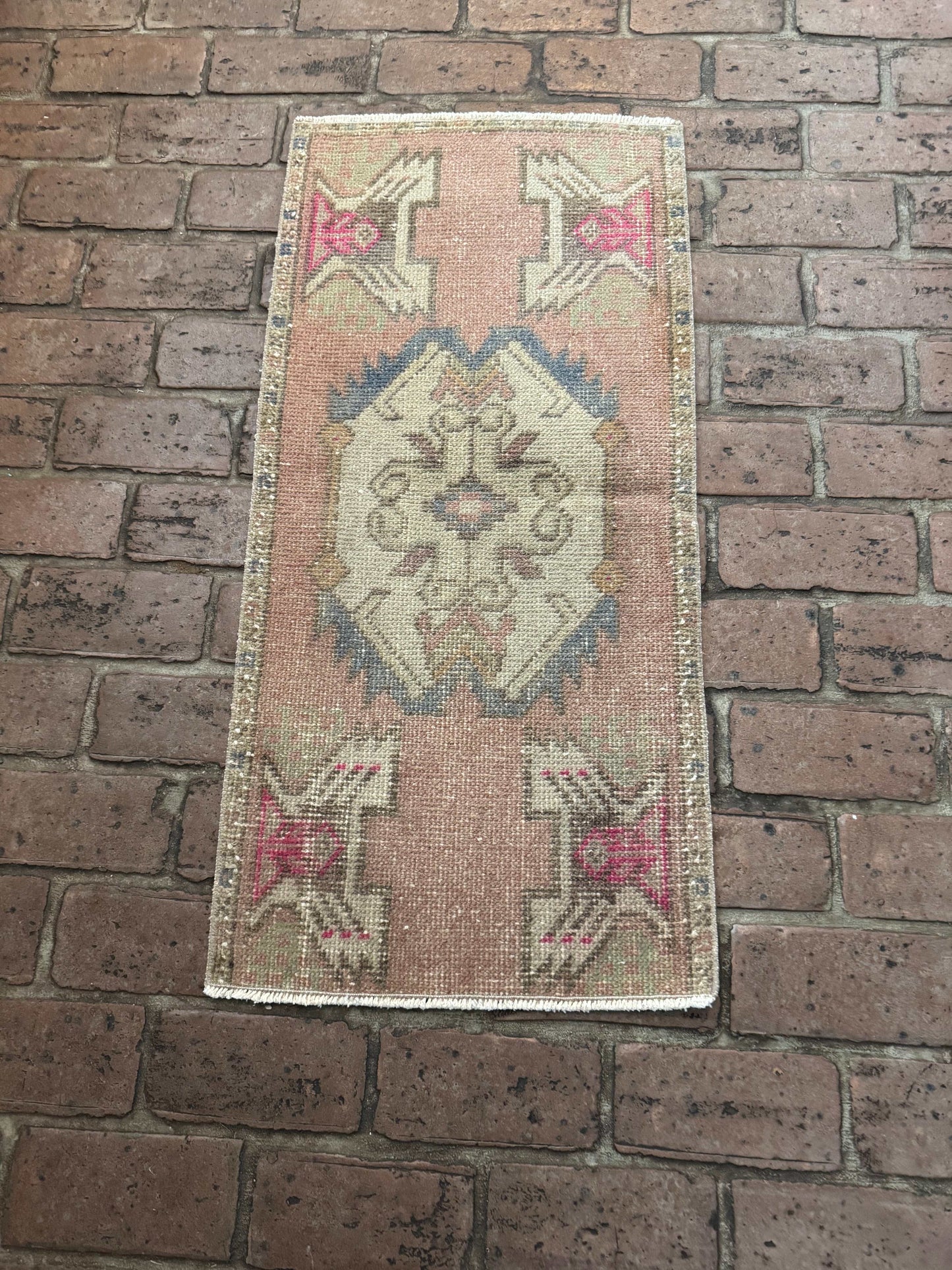 1'6" x 3'3" Turkish Rug with mauve pink, gray-blue, brown, and hot pink accents on brick floor