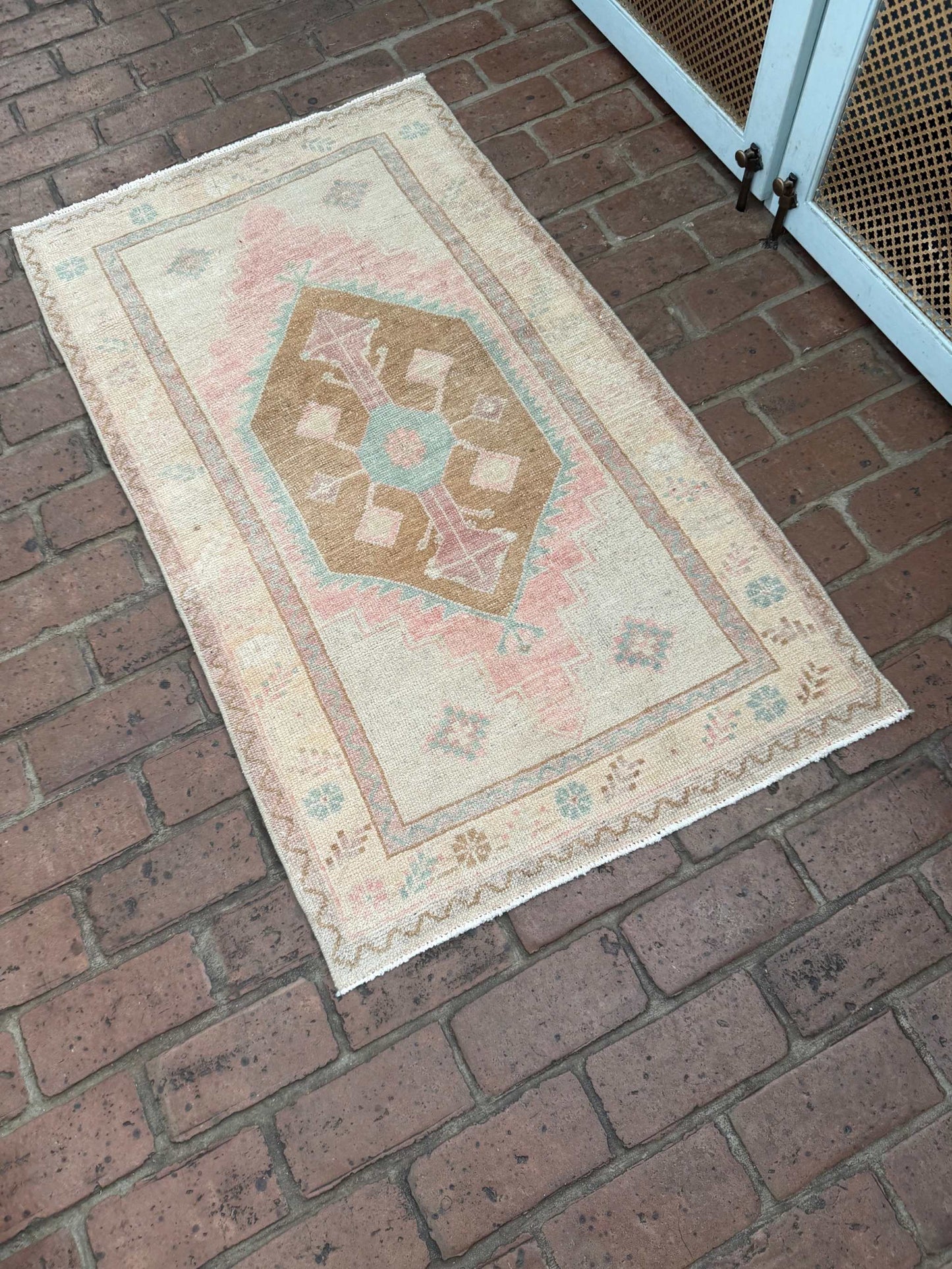 Small colorful area rug with pink, blue, and brown center medallion design measuring 2'4" x 4'3"