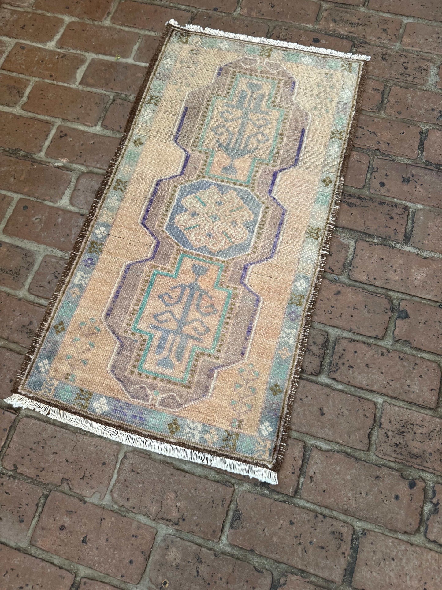 Small Turkish Oushak rug with a brown background, featuring purple, green, and brown border patterns.