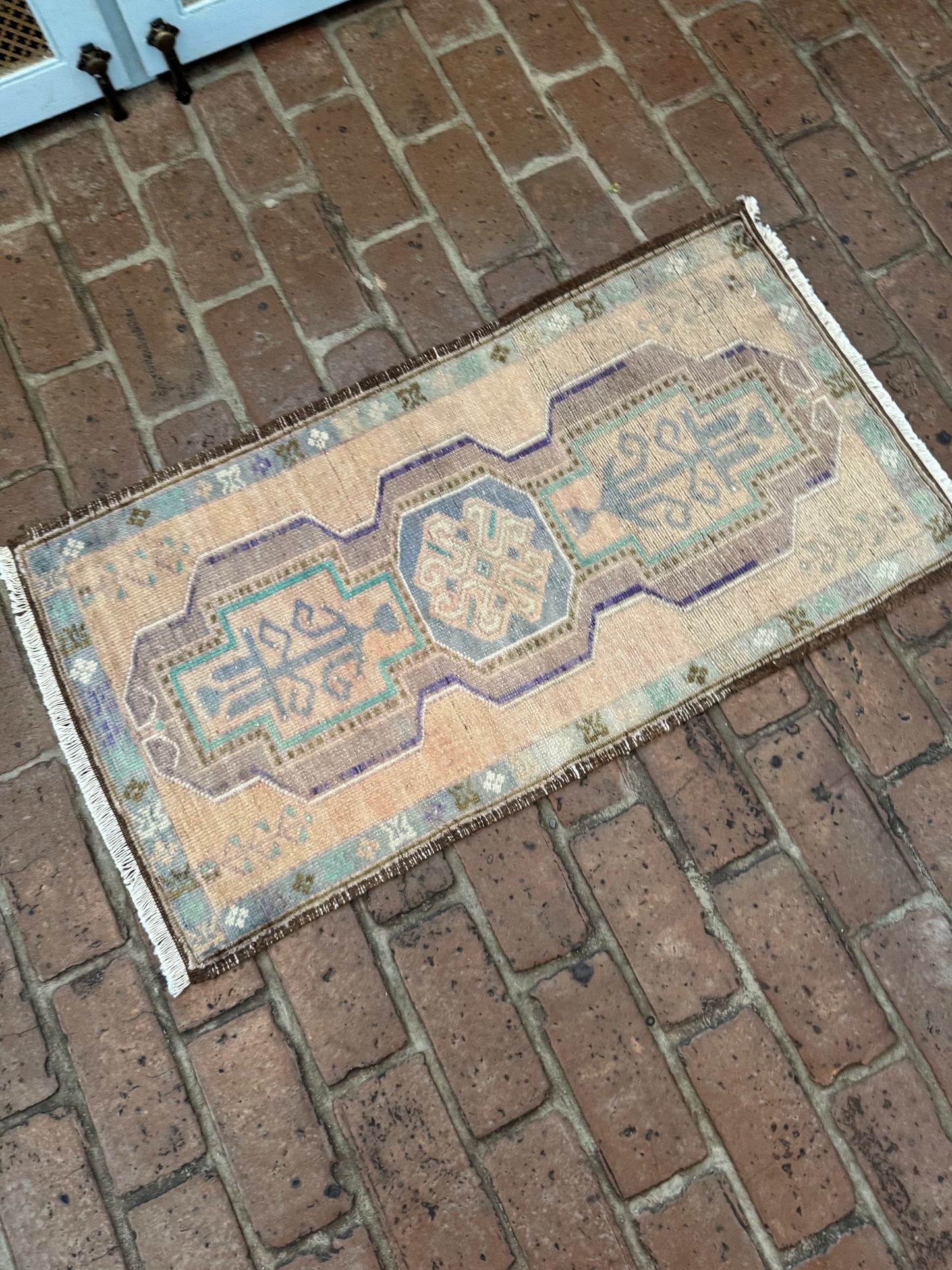 Small Turkish Oushak rug with brown background and purple, green, and brown border.