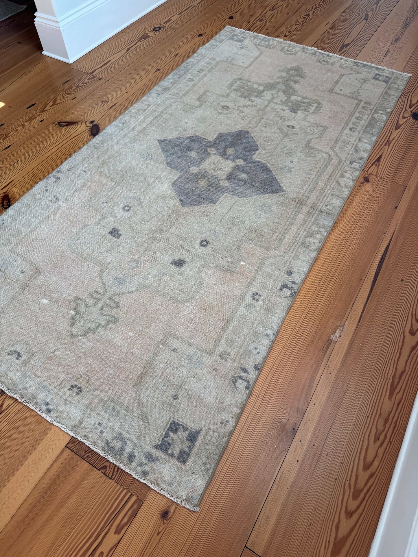 4'1" x 8'5" area rug with blush tones and gray-purple medallion on wood floor.