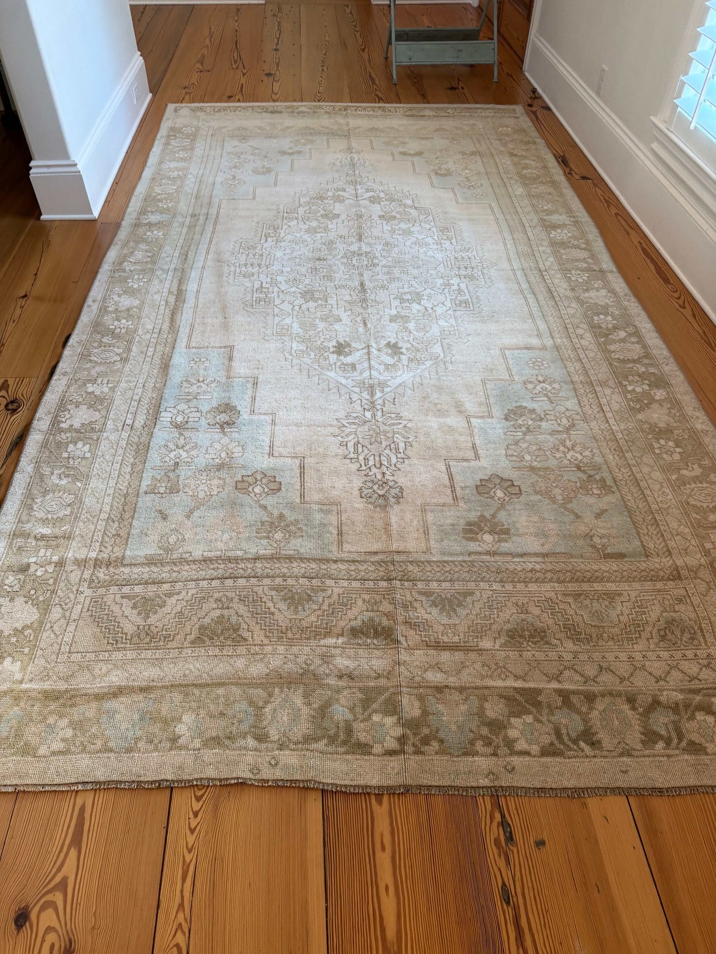 Large patterned rug on a wooden floor with a white wall in the background