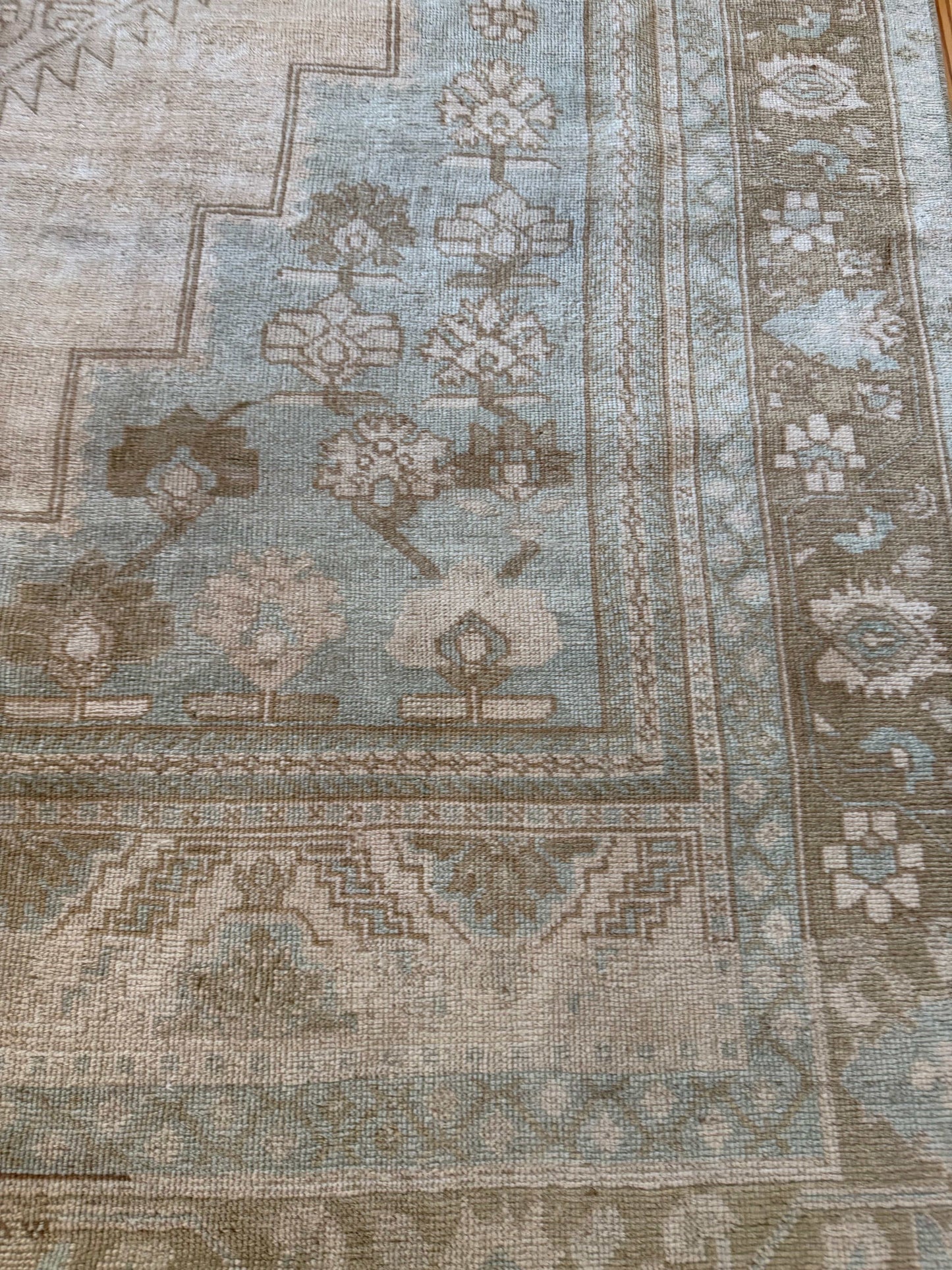 Close-up of a patterned rug with geometric designs in shades of brown and beige.
