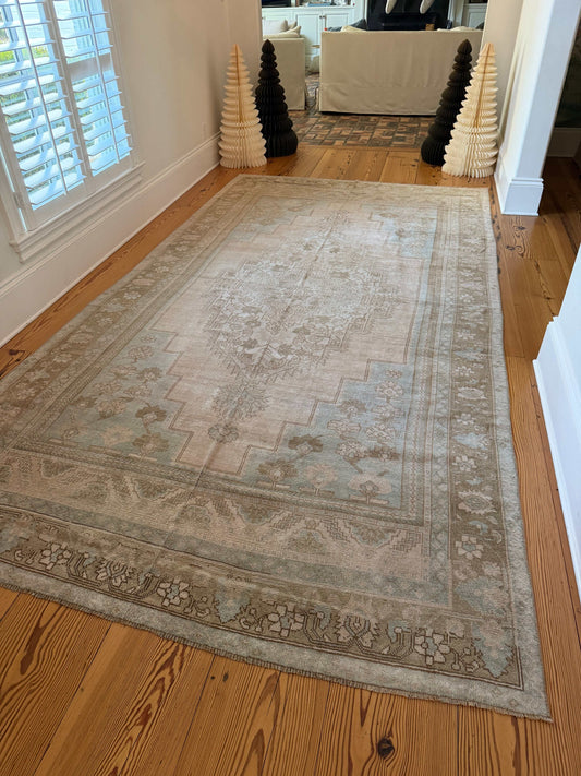 Large decorative rug on a wooden floor with a neutral color palette