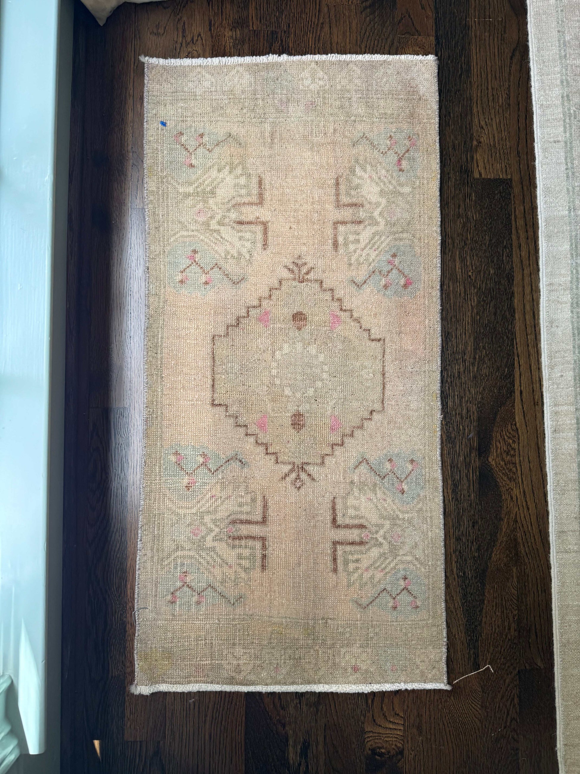 1’5” x 3’1” mini rug with geometric pattern on wooden floor.