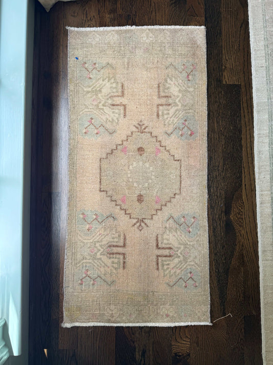 1’5” x 3’1” mini rug with geometric pattern on wooden floor.