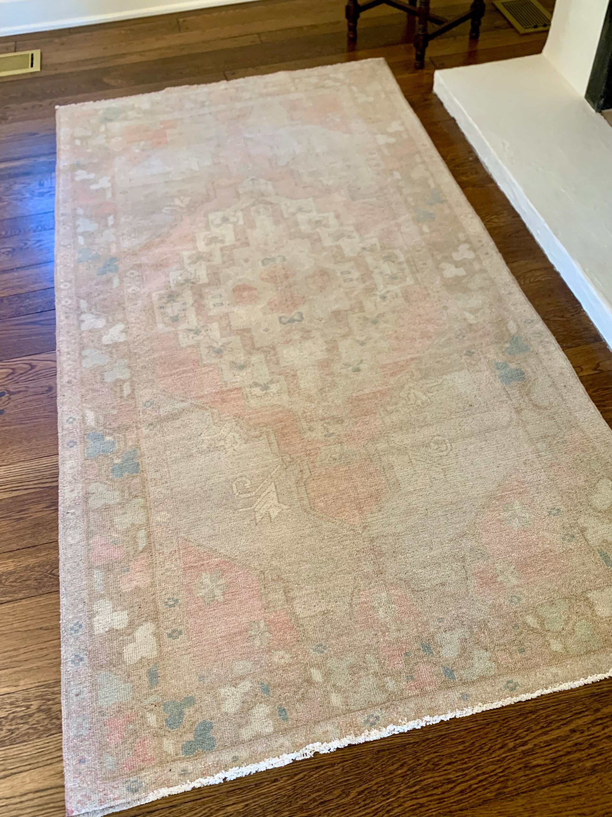 4’7”x8’9” vintage Oushak area rug with muted red, beige, blue, and cream design.