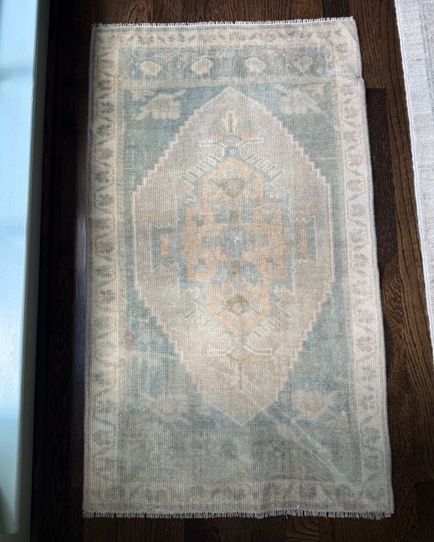 1’9” x 3’ mini rug with a subtle patterned design in soft tones.
