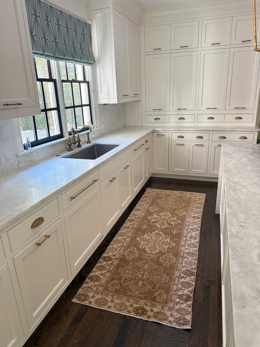 Vintage Oushak runner rug in brown, beige, cream, blue, and blush colors in a white kitchen setting