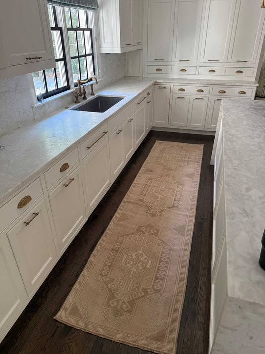 2’8” x 11’ runner in ivory, beige, and brown tones on dark hardwood kitchen floor between white cabinets