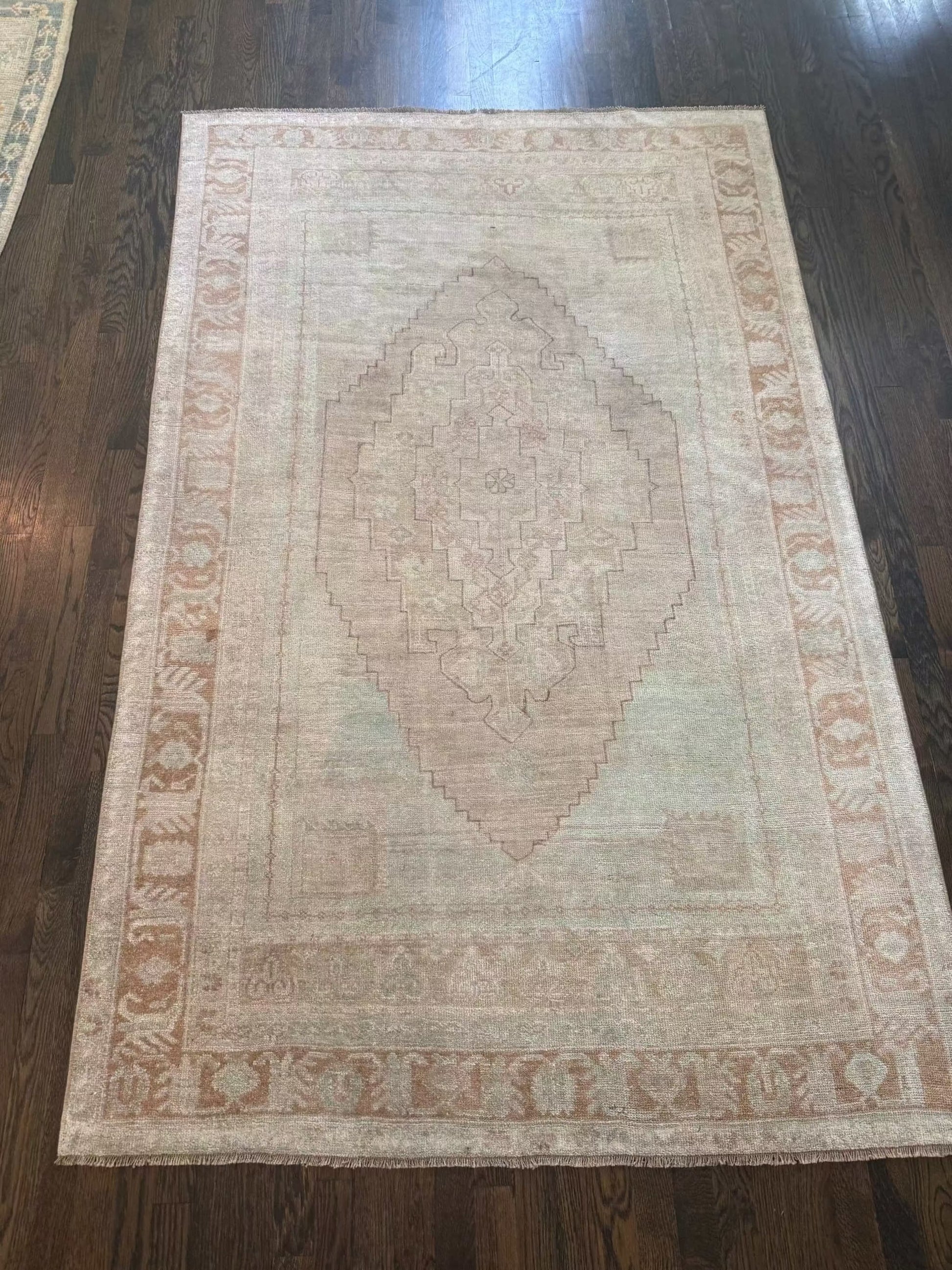 4’7” x 7’3” vintage area rug with light blue, beige, grey, brown, soft green, and muted yellow colors
