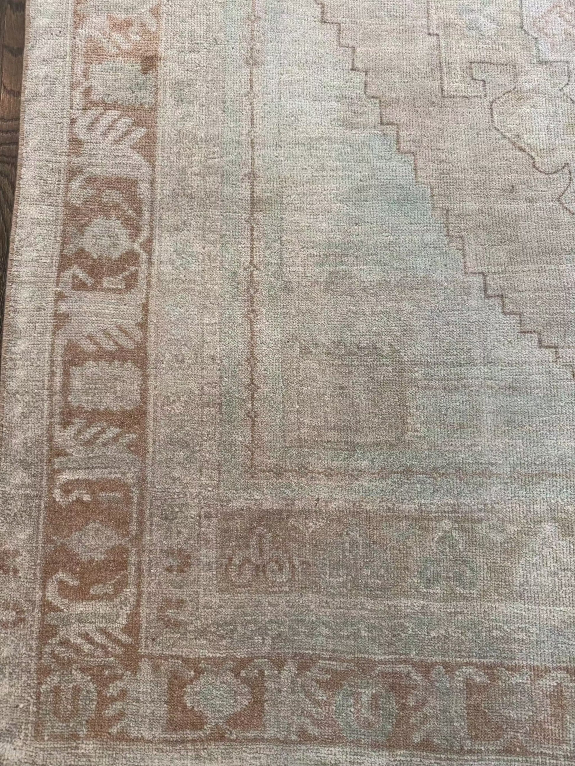 4’7” x 7’3” vintage area rug with light blues, beige, grey, brown, soft greens, and muted yellows