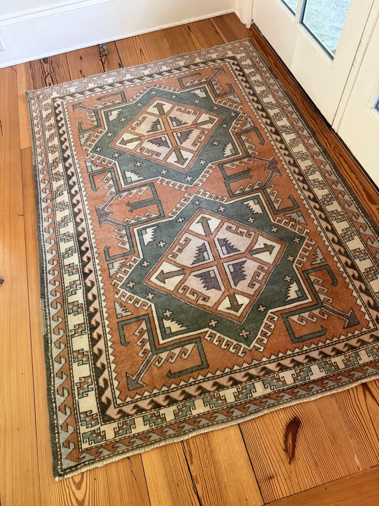 4' x 5'10" area rug with rust and gray double medallion design on hardwood floor