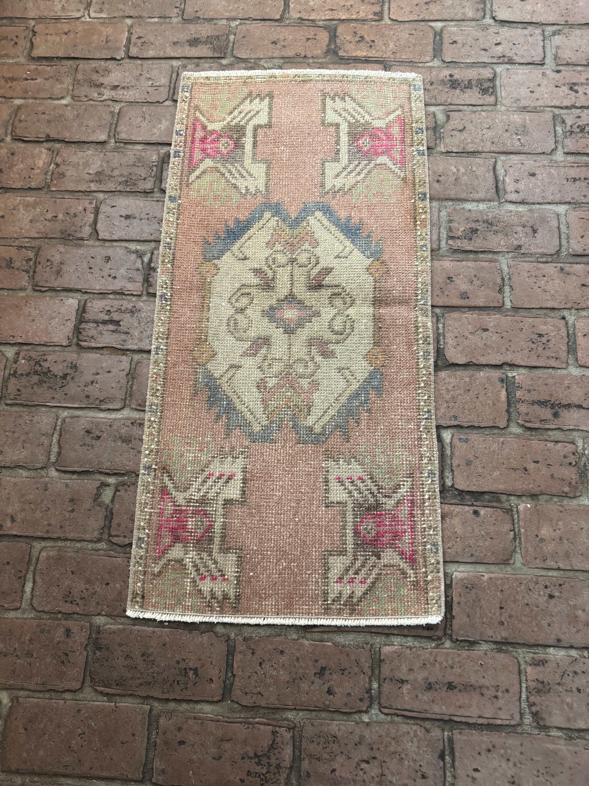 1'6" x 3'3" Turkish Rug with mauve pink, gray-blue, brown, and hot pink accents on brick floor