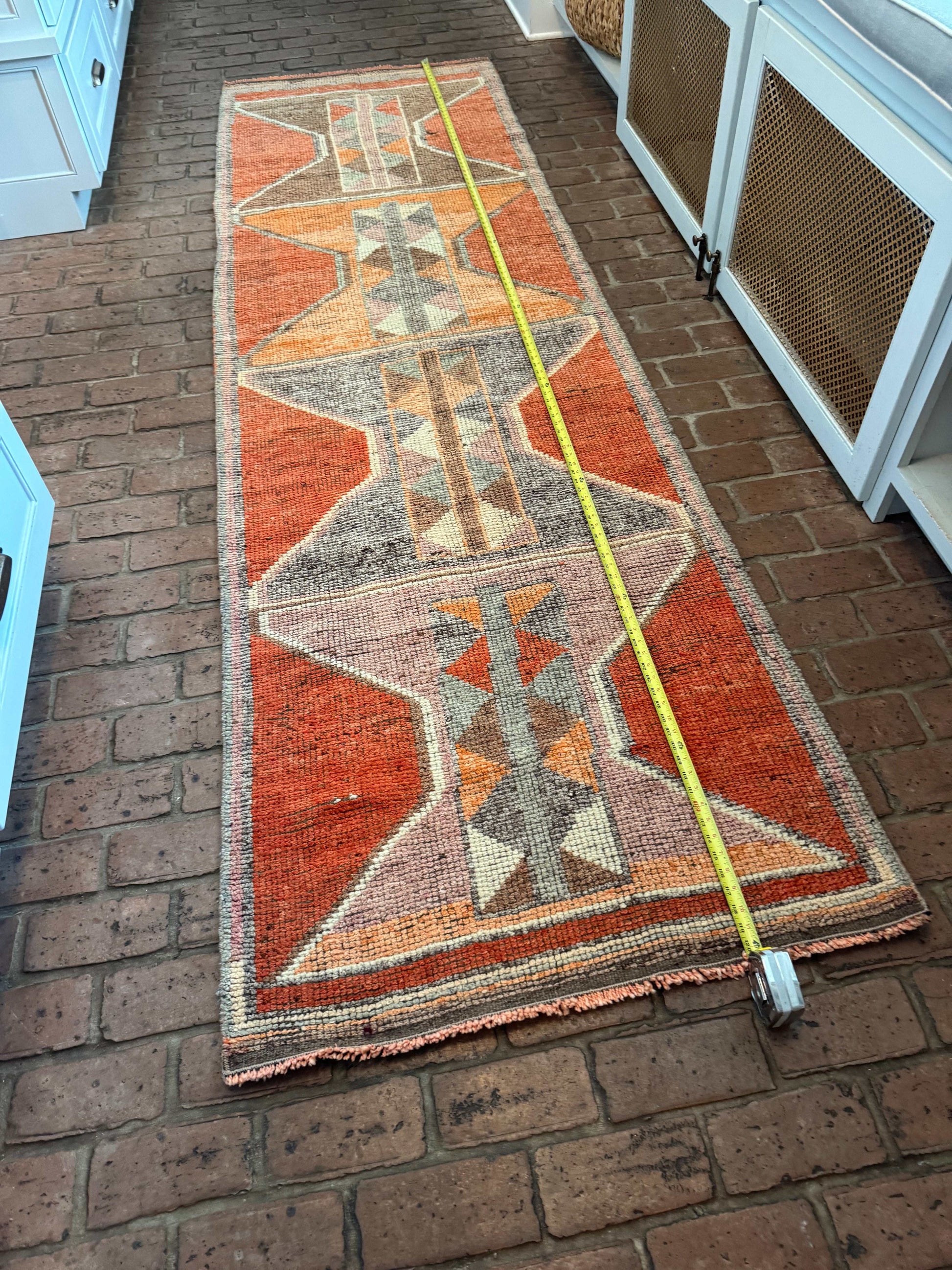3 x 10 orange and gray geometric patterned rug runner on brick floor measuring length