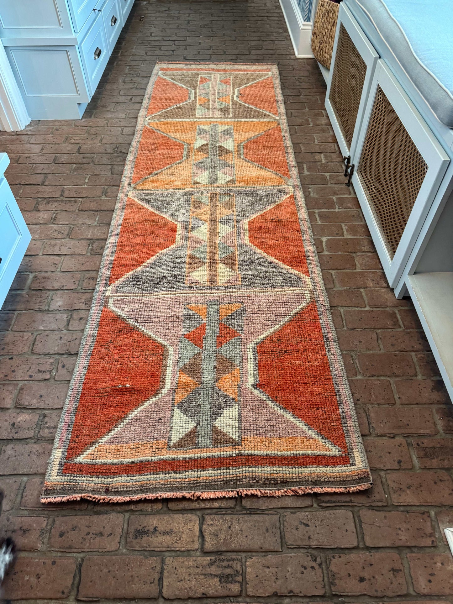 Decorative rug with geometric pattern on a brick floor