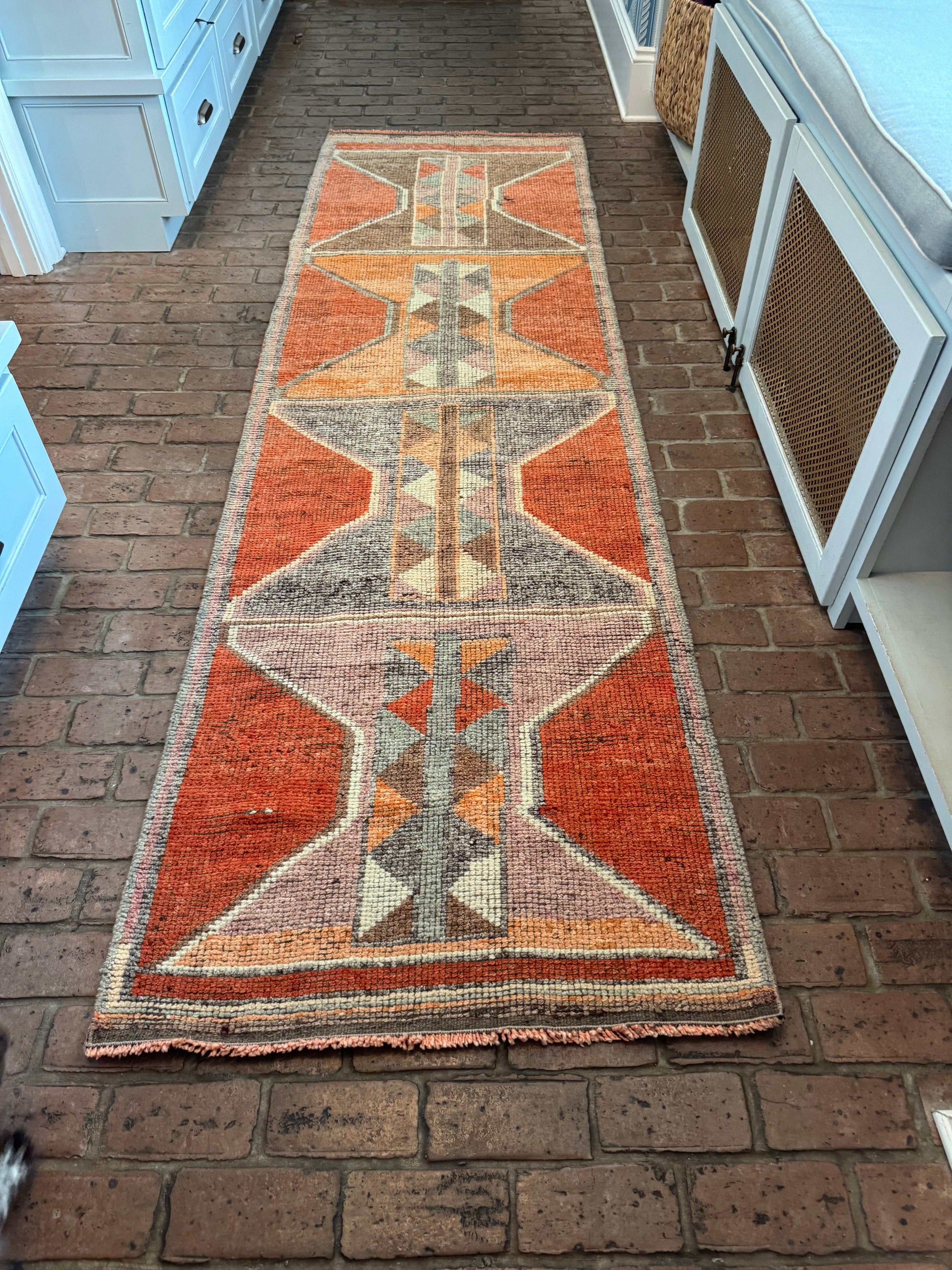 Decorative rug with geometric pattern on a brick floor