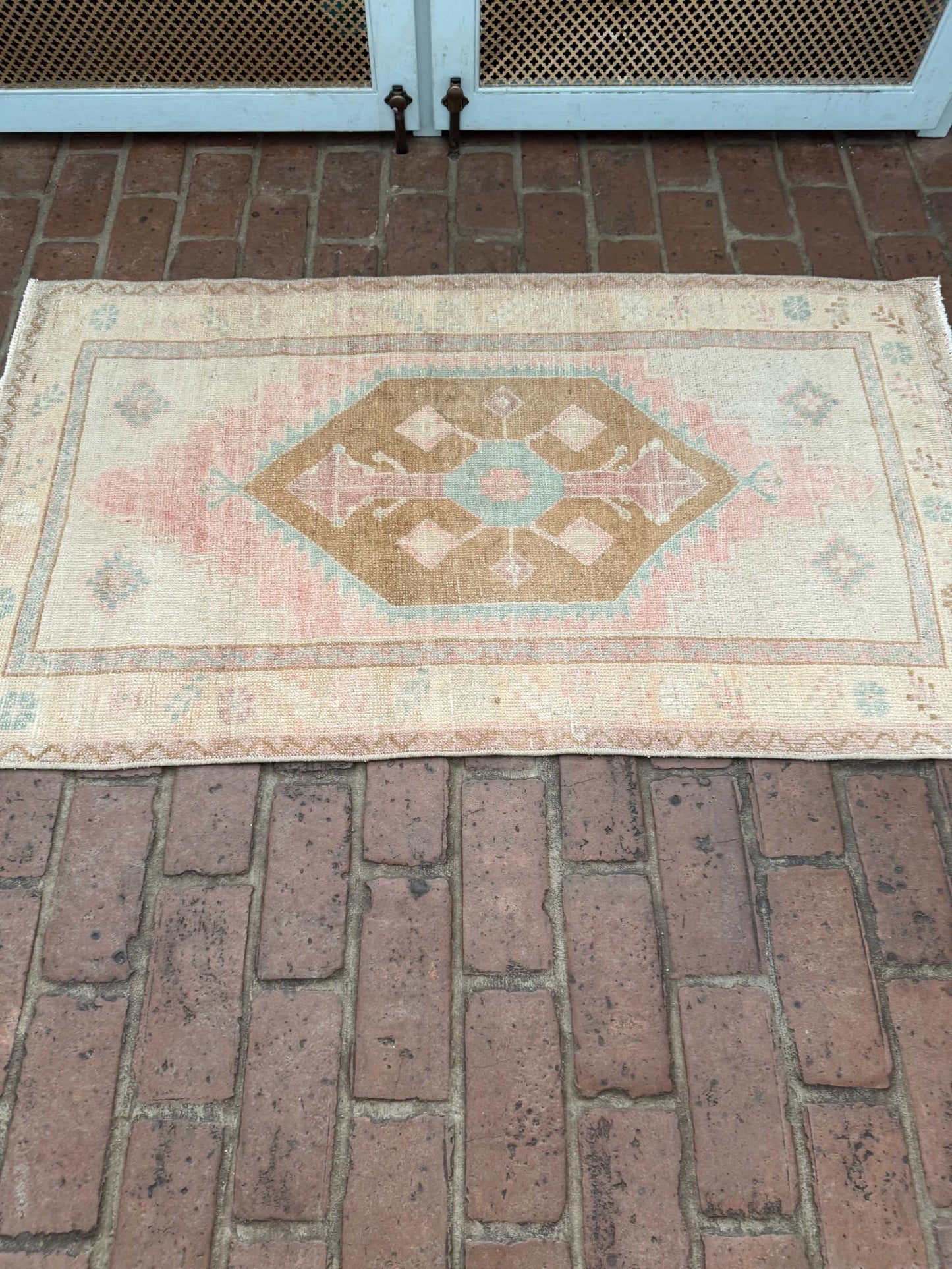 Small colorful area rug with pink, blue, and brown center medallion design measuring 2'4" x 4'3"