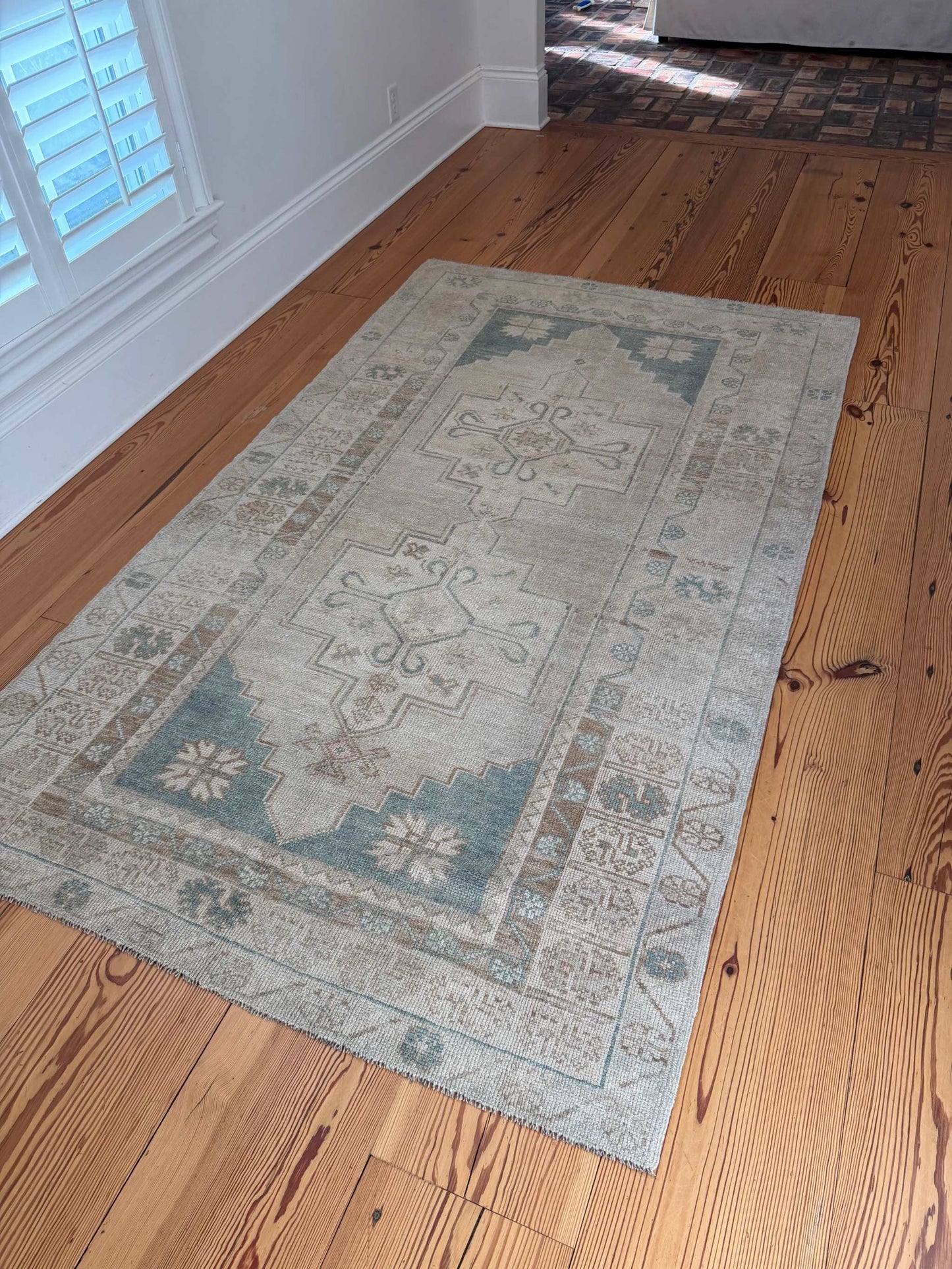 4'8" x 8'1" hand knotted area rug with neutral background and teal blue-green medallions