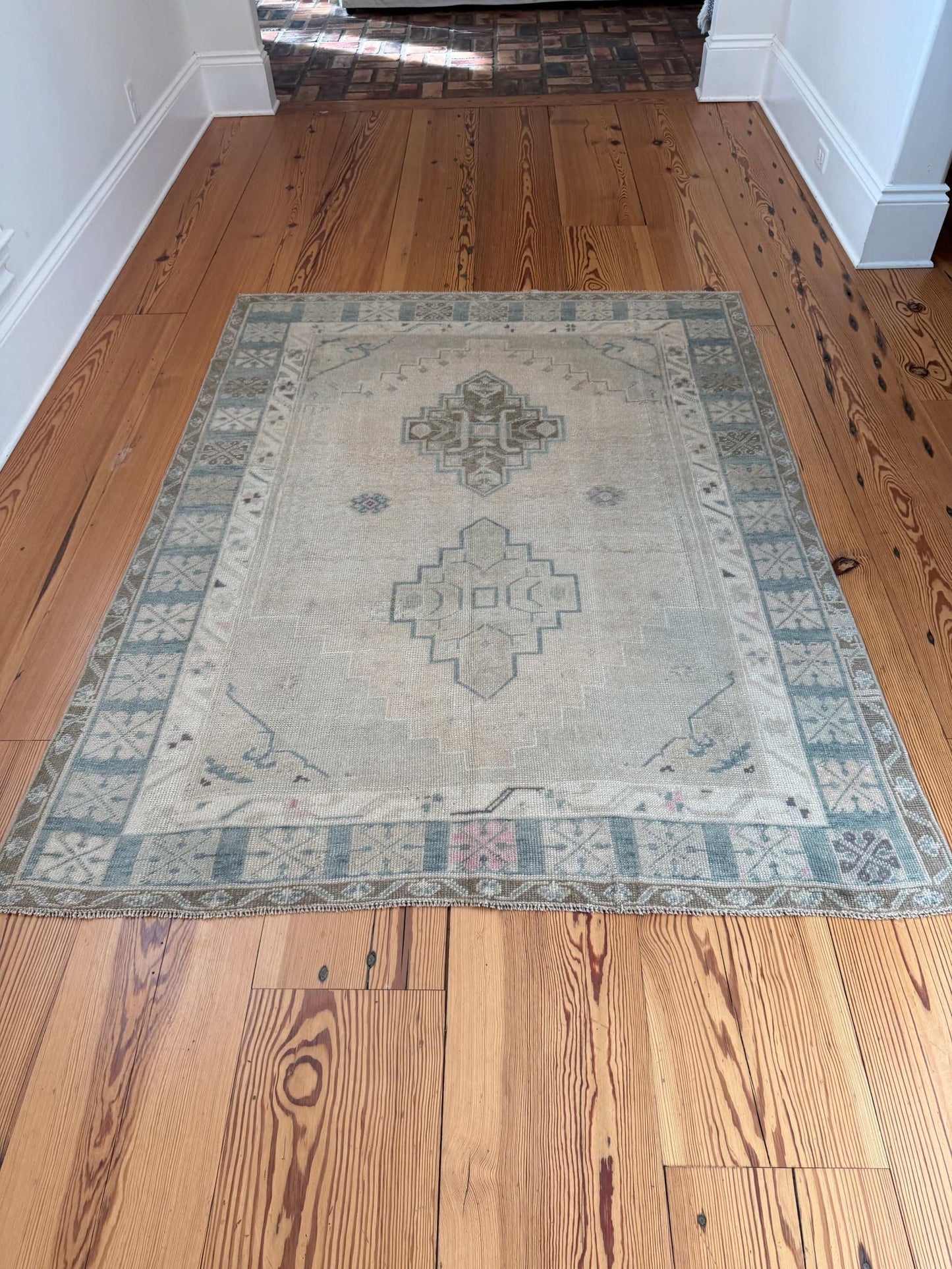 4'11" x 6'6" hand-knotted Turkish square area rug with neutral background and blue-green, hot pink accents