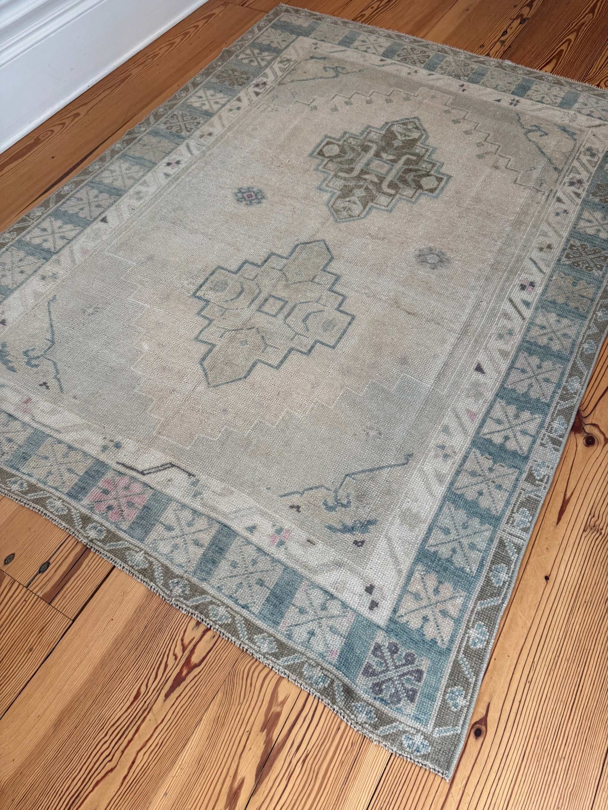 4'11" x 6'6" square area rug with neutral background, blue-green tones, and pink accents, hand-knotted Turkish design