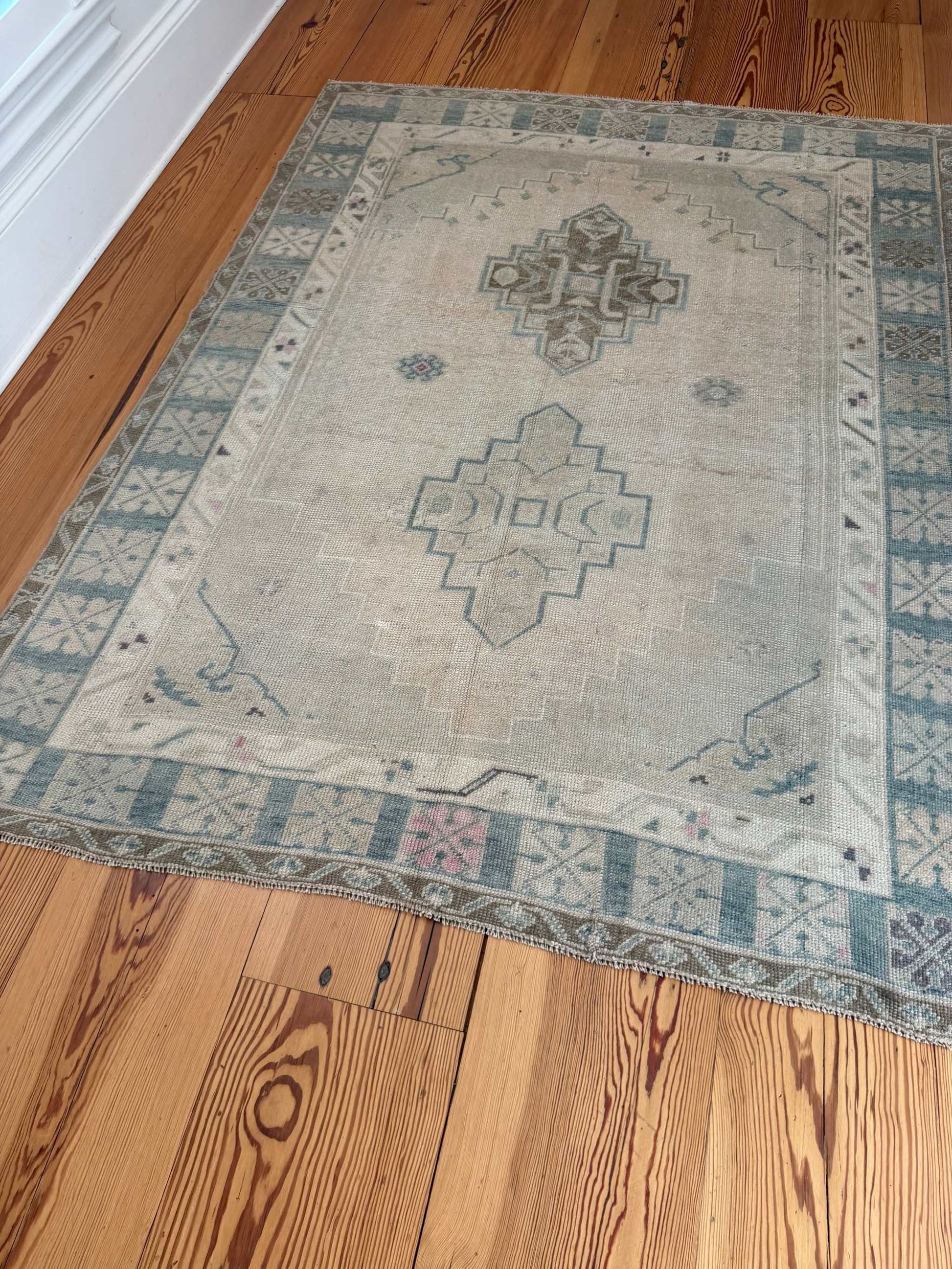4'11" x 6'6" square area rug with neutral background, blue-green hues, and pink accents, hand knotted Turkish design