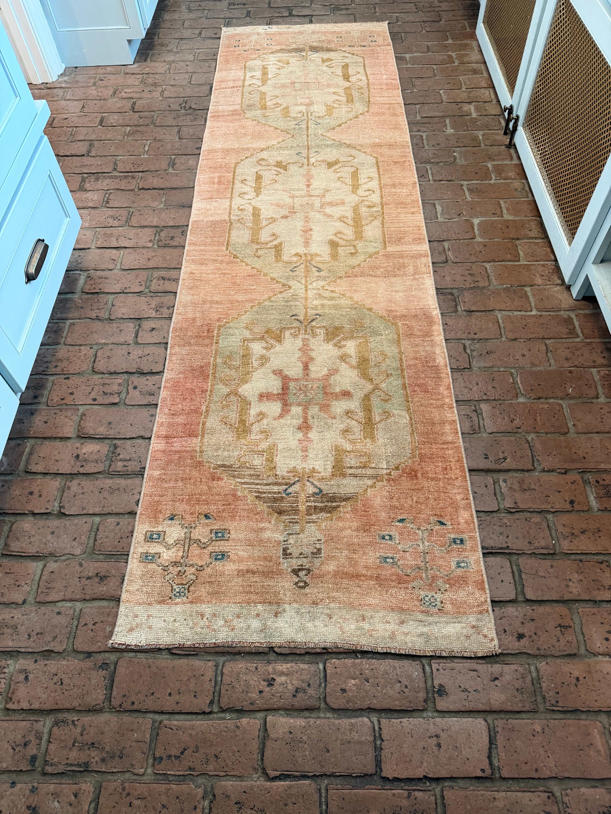 Long rectangular rug with a geometric pattern on a brick wall.