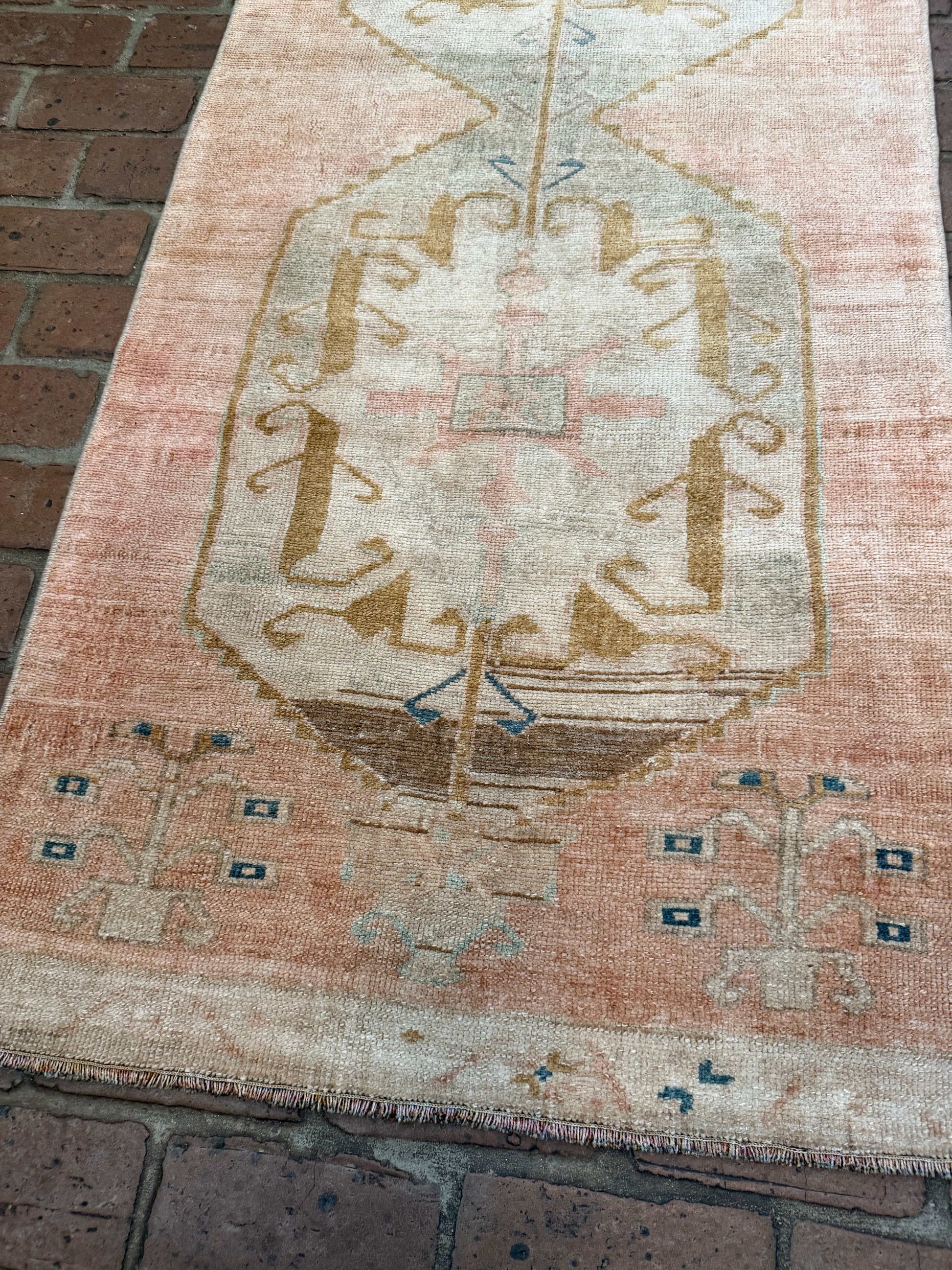 Close-up of a patterned rug with intricate designs on a brick floor.