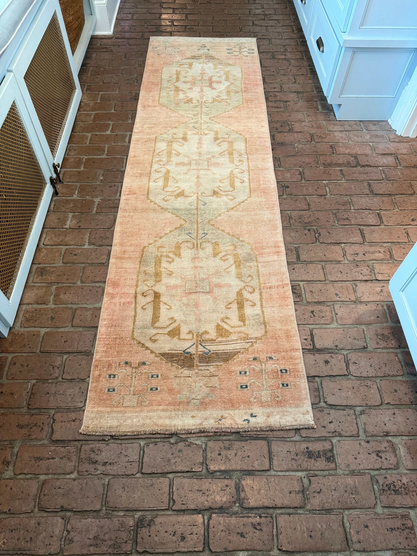Long rectangular rug with a geometric pattern on a brick wall.