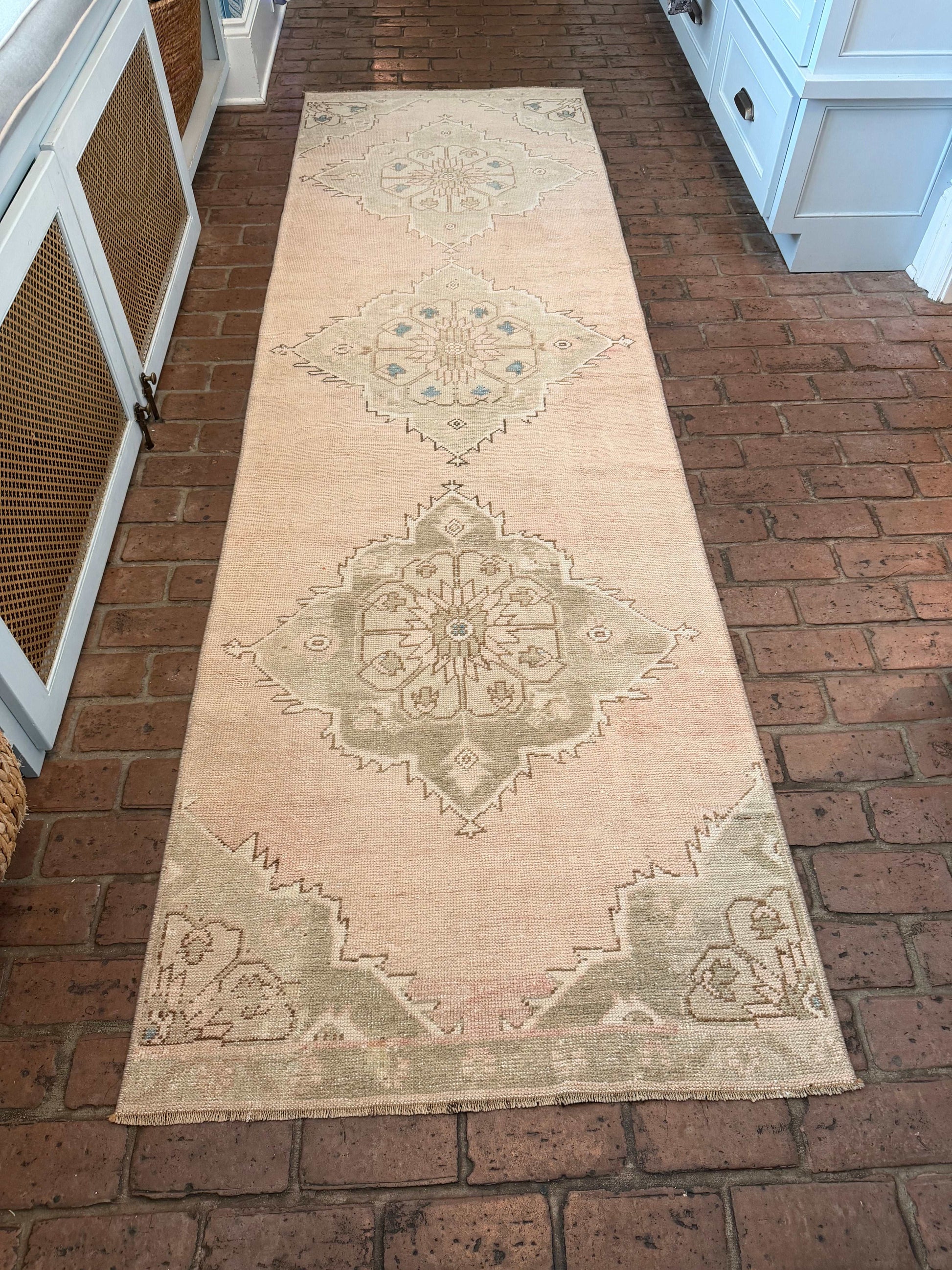 Long rectangular rug with geometric pattern on a brick floor