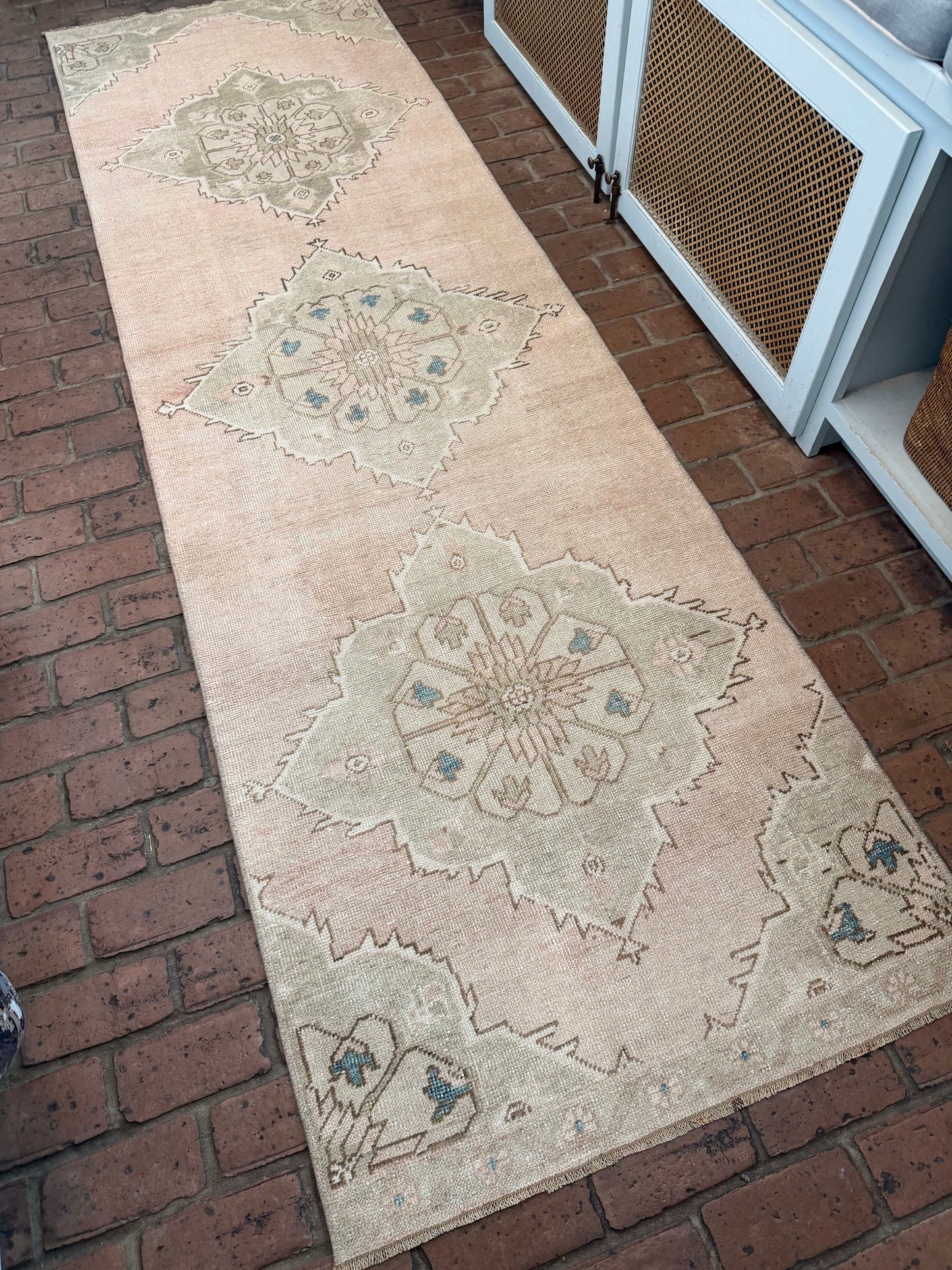 Long rectangular rug with geometric pattern on a brick floor