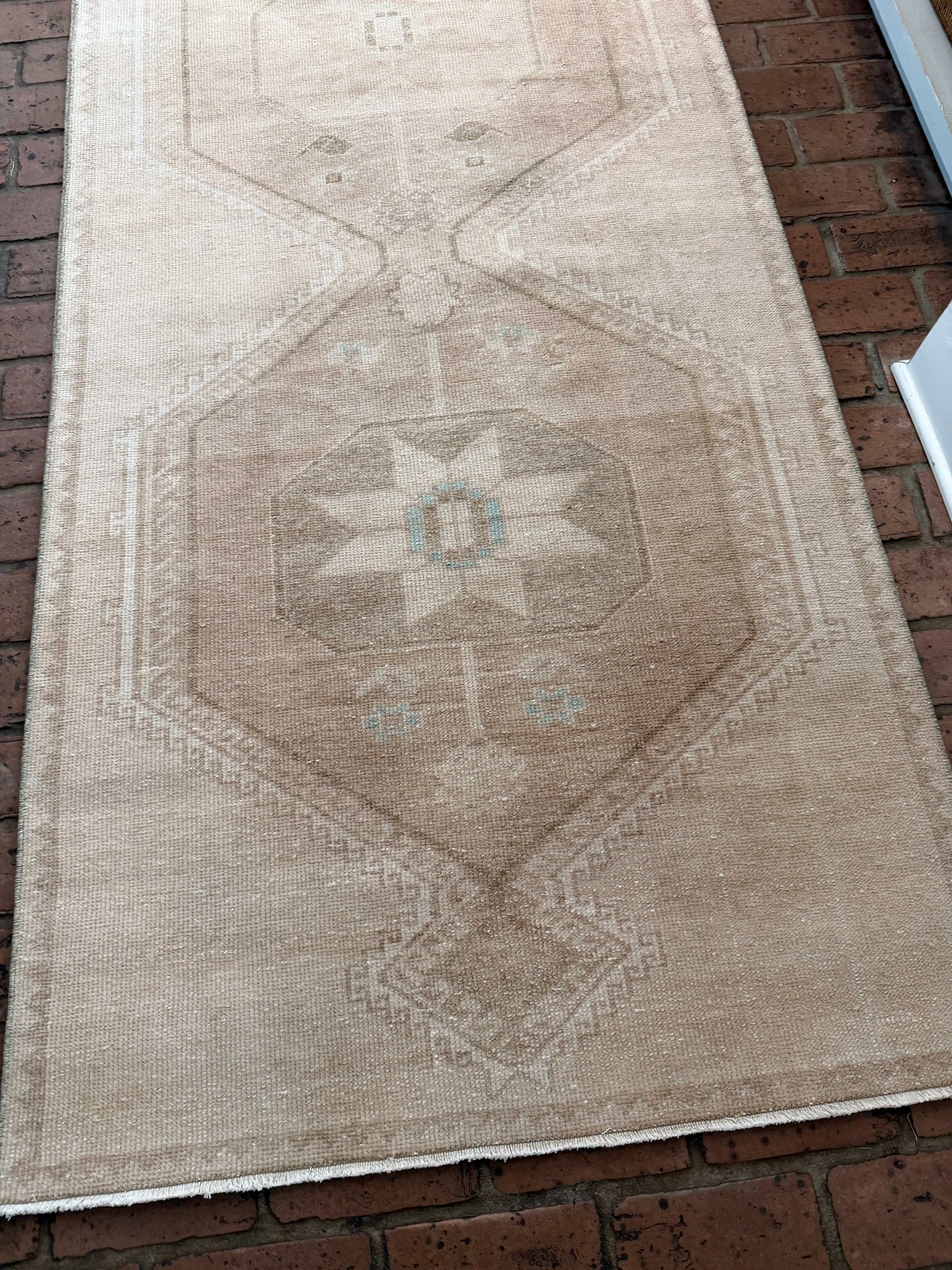 Beige area rug with geometric pattern on a brick floor