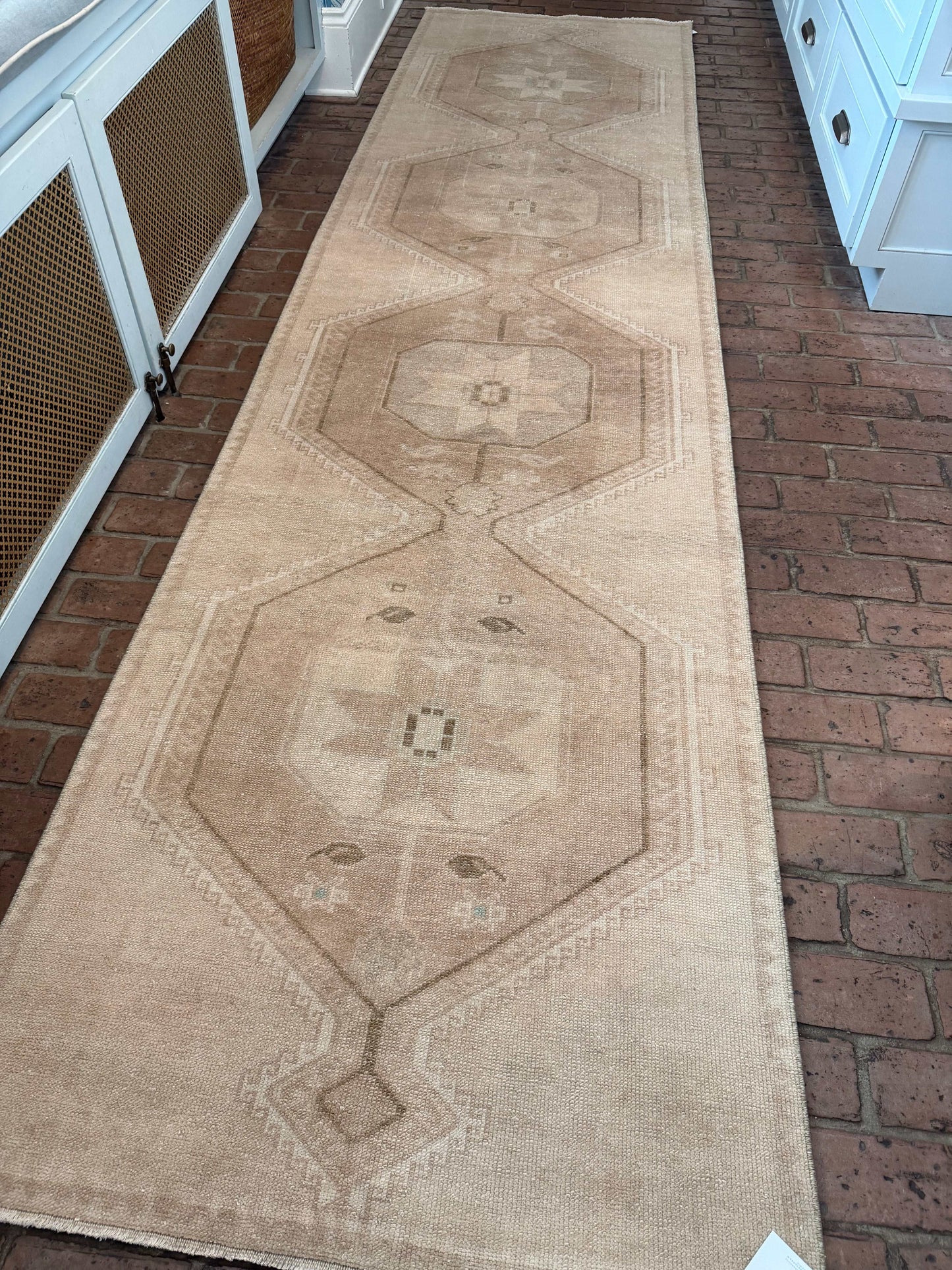 Long beige patterned rug on a brick floor